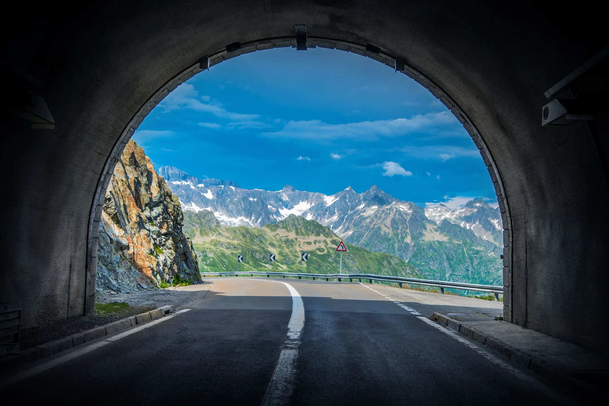 Riding out of a mountain tunnel into the Alps